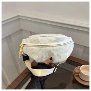 Detalle de la riñonera crema con textura de sarga y tirador de cremallera amarillo vibrante