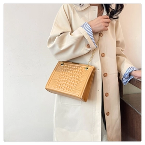 Detail of yellow crocodile embossed texture on trendy tote bag with gold chain strap