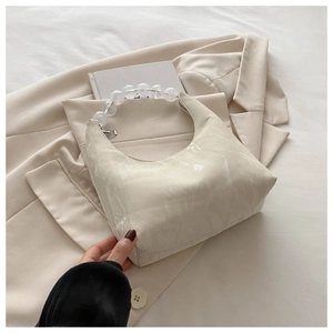 Detail of hobo crescent bag with acrylic bead handle on stylish beige blazer fabric