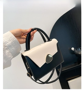 Detail of contrast stitching and semi-circular metal clasp on a black and white bag