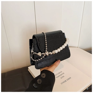 Detail of black faux crocodile skin mini flap bag with pearl handle and silver chain strap