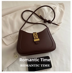 Brown leather crescent bag detail with gold clasp shown next to a smartphone
