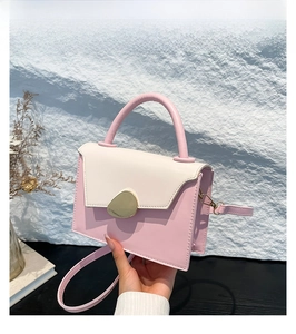 Detail of pink and beige crossbody bag with gold metal buckle and round handle