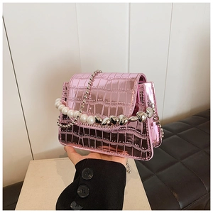 Detailed shot of pink crocodile pattern mini flap bag with decorative heart pearl chain