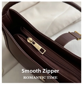 Close-up of durable golden metal zipper on dark brown leather shoulder bag detail