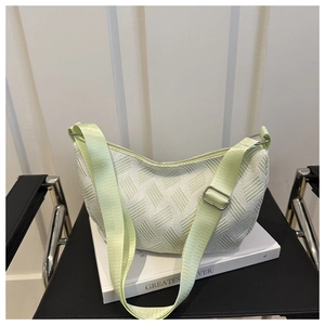 Detail of light green nylon dumpling bag with textured fabric and wide adjustable strap