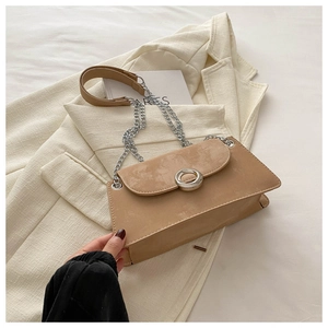 Détail du sac camel avec boucle magnétique argentée et bandoulière chaîne sur blazer