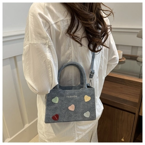 Detailed view of grey bucket bag with colorful heart patches and adjustable shoulder strap