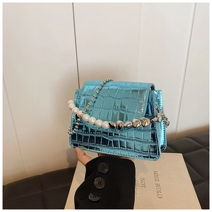 Detail of mini faux crocodile leather bag with pearl and heart chain handle in metallic blue