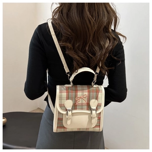 Close-up of retro plaid backpack featuring cream leather trim and a pink bow embroidery