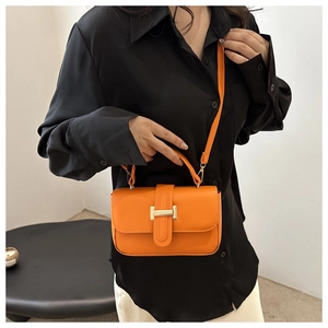 Dettaglio della mini borsa quadrata in pelle arancione vivace con fibbia dorata su camicia