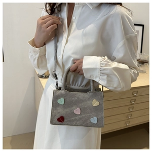 Detail of grey suede handbag featuring colorful heart patches and fashion embroidery