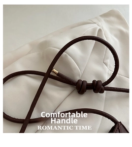 Detailed close-up of dark brown leather shoulder strap with knot and golden metal hardware