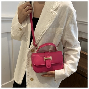 Dettaglio mini borsa quadrata fucsia con fibbia dorata su sfondo blazer bianco