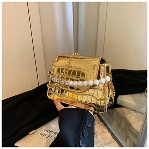 Detail of gold crocodile embossed mini flap bag with pearl handle and metal chain