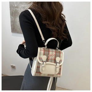 Detail view of mini plaid backpack with pink bow embroidery and dual buckled flap closure