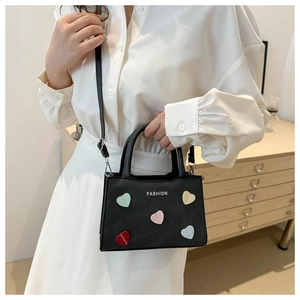 Detail of black leather handbag with colorful heart patches and fashion text logo