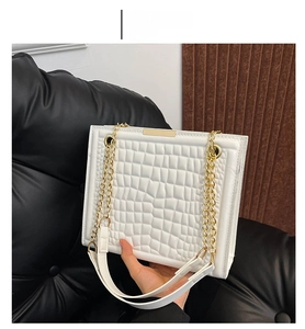 Detail of white crocodile pattern tote bag with chunky gold chain and leather strap