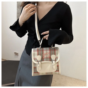 Detail of vintage plaid crossbody bag with pink bow embroidery and metal buckles