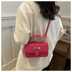Dettaglio della borsa rosa con fibbia dorata indossata su un blazer bianco