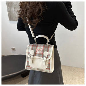 Detail of a vintage plaid mini backpack with pink bow embroidery and white leather flap