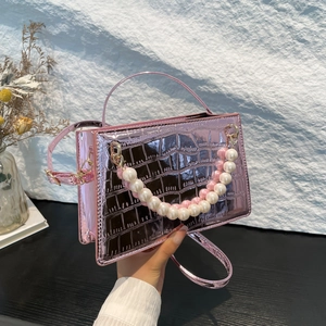Pink metallic crossbody bag with crocodile pattern and pearl chain handle detail