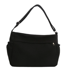 Large black canvas tote bag with adjustable shoulder strap and side pockets on white backdrop
