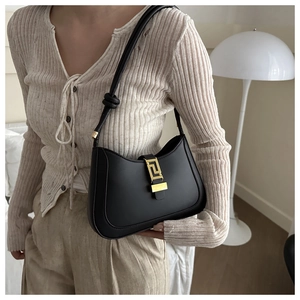 Detail of black crescent shoulder bag with golden geometric buckle and knotted strap