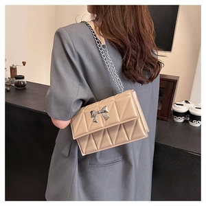 Détail du sac beige en similicuir matelassé avec boucle nœud argenté porté au dos