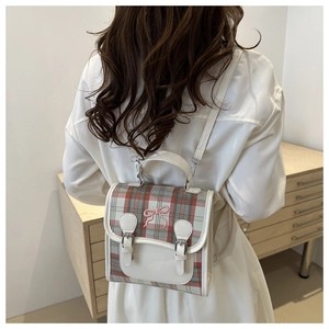 Detail of vintage beige leather backpack with plaid fabric and pink bow embroidery
