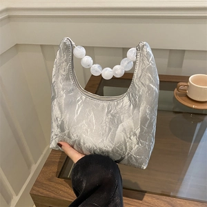 Silver textured crescent bag with large marble bead handle shown in a cozy indoor setting