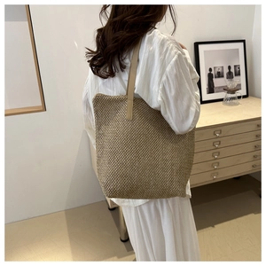 Dettaglio della grande borsa tote in paglia intrecciata con spalline in pelle marrone