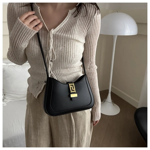 Close-up of golden rectangular lock with geometric patterns on black leather bag