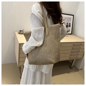 Dettaglio della trama a rete intrecciata e tracolla in pelle di una borsa tote beige