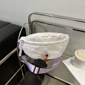 Sac banane matelassé blanc avec sangle violette et détails de zip dans un décor de style de vie