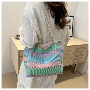 Rainbow woven tote bag worn on shoulder featuring colorful stripes and leather strap