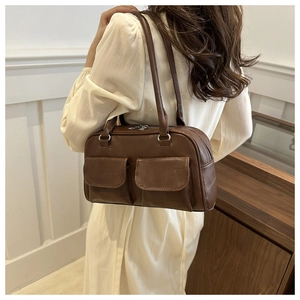 Dunkelbraune Retro-Lederschultertasche mit zwei Vordertaschen an einem Modell