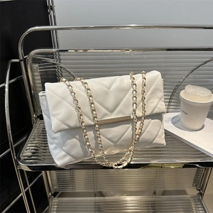 Borsa a tracolla trapuntata bianca con motivo a V e fibbia in oro su uno scaffale