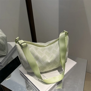 Light green nylon dumpling bag with adjustable wide strap on minimalist decor background