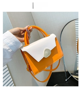 Detail of trendy orange and white patchwork handbag featuring a modern silver metal buckle