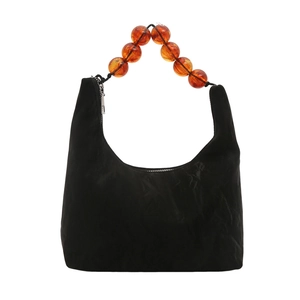 Minimalist black crescent shoulder bag with vintage amber bead handle on white background