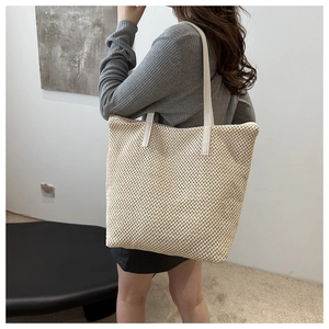 Dettaglio della borsa tote in tessuto con tracolla in pelle indossata su una spalla