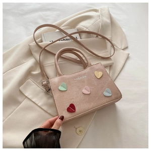 Detail of pink faux suede bucket bag with colorful heart patches and fashion text