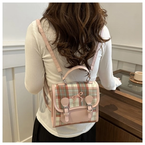 Detail of a mini plaid backpack with pink bow embroidery and leather strap textures