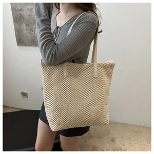 Dettaglio borsa tote in paglia beige con manici in pelle chiara e zip in metallo resistente