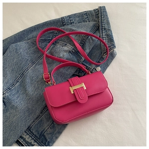 Dettaglio della mini borsa a tracolla rosa acceso su denim con chiusura dorata