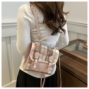 Detail of pink plaid mini backpack with leather bow and adjustable straps on female model