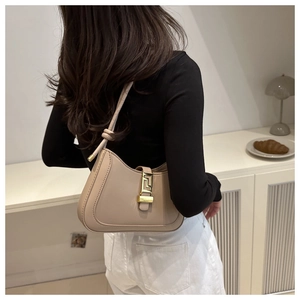 Detail of a beige leather shoulder bag with a gold buckle and knotted strap detail