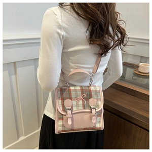 Detail of checkered mini backpack with pink bow and green plaid pattern on a model
