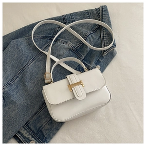 Dettaglio borsa quadrata bianca con fibbia dorata su sfondo in tessuto denim blu